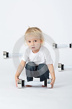 A little boy sitting with dumbbell