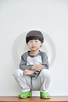 Little boy sitting on the floor Isolated on white wall