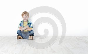 Little boy sitting on floor leaning against wall