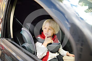 Little boy is sitting in the front seat of car. Child travels with single parent. Safety of transportation of kids