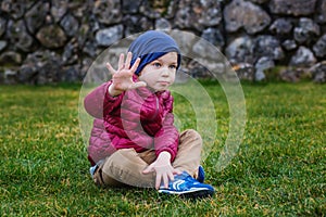 A little boy sitting on the grass