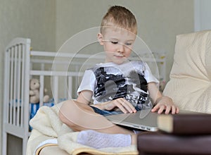 Little boy sitting with laptop on the couch at home