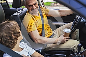 Little boy sitting near his mature father in the car