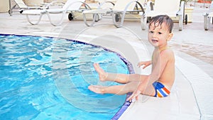 The little boy is sitting poolside at the resort