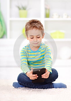 Little boy sitting and reading from tablet