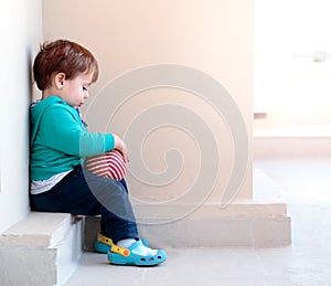 Little boy sitting with a rubber ball in his hands.