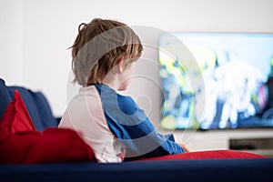 little boy sitting on a sofa watching TV