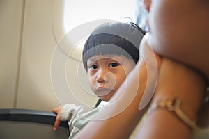 Little boy sitting at window seat in airplane : looking at camera