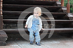 A little boy sitting on wooden stairs