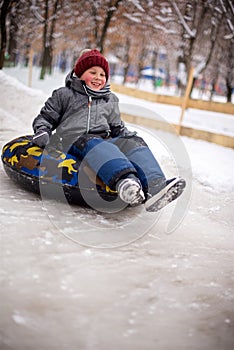 A little boy on a sled and goes down an ice slide