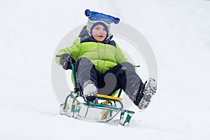 Little boy sled ride on snow mountain in winter