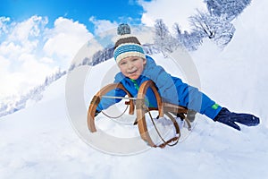 Little boy on sledge slide from the mountain