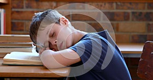 Little boy sleeping on a book in classroom