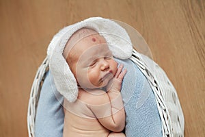 Little boy sleeps in a basket with a white blanket