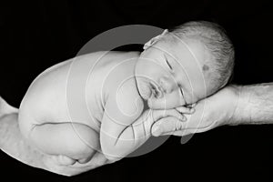 A little boy sleeps in his dad`s arms.