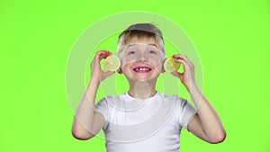 Little boy with slices of lemon licks them and shows grimaces. Green screen. Slow motion