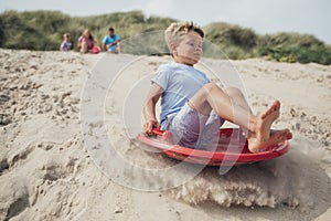 Little Boy Sliding Down a Sand Dune