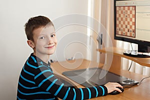 Little boy smile and play online chess