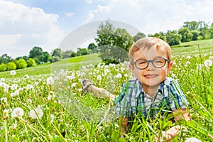 Little boy smiles laying on a grass