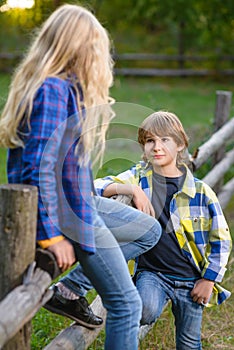 Little boy smiling and girl on fence looking at