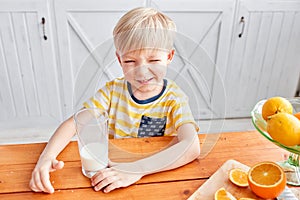 Little boy are smiling while having a breakfast in kitchen. Mom is pouring milk into glass