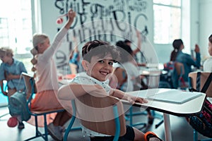 Little boy smiling sitting in the back of the classroom.