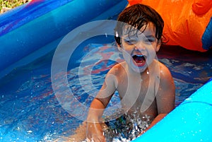 Little boy smiling and splashing in a pool