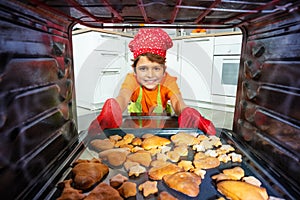 Little boy smiling take cookies tray from oven
