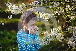 Little boy sneezes because of an allergy to pollen. photo