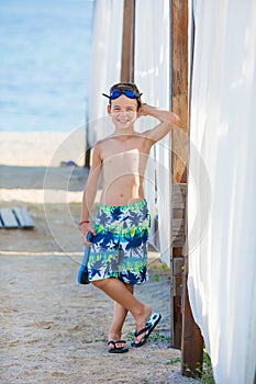 Little boy with snorkel by the sea. Cute little kid wearing mask and flippers for diving at sand tropical beach. Ocean coast