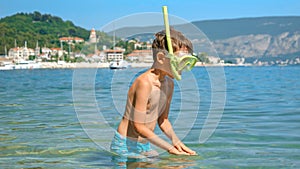 Little boy with snorkeling mask and breathing tube swimming and diving at the sea beach.