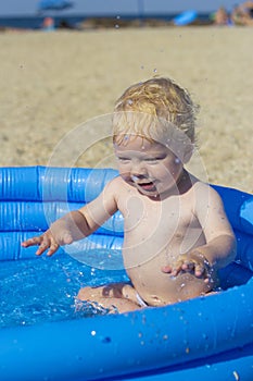 A little boy splashing in an inflatable pool