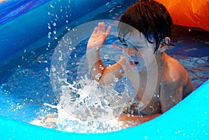 Little boy splashing in a pool