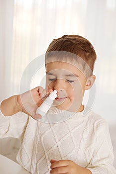 Little boy spraying medicine in nose, nose drops. Toddler child using nasal spray. Runny nose, cold, flu, illness, virus