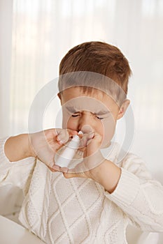 Little boy spraying medicine in nose, nose drops. Toddler child using nasal spray. Runny nose, cold, flu, illness, virus