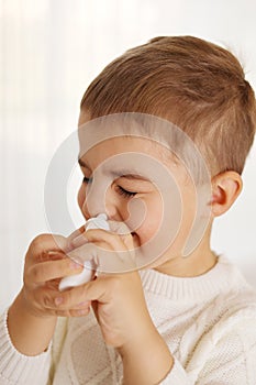 Little boy spraying medicine in nose, nose drops. Toddler child using nasal spray. Runny nose, cold, flu, illness, virus