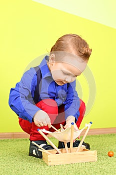 A little boy squatting and playing with wooden
