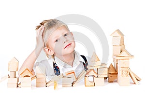 Little boy stacks house from wooden blocks isolate