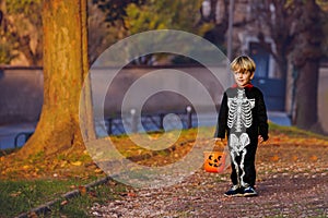 Little boy stand in Halloween skeleton disguise with bucket