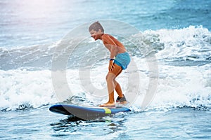 Little boy stand on the surfboard learn to ride