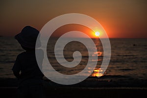 Little boy standing back and watching the sunset