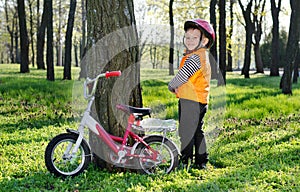 Little boy standing grinning alongside his bicycle