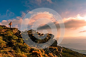 A little boy standing on a large rocky rock admires the landscape of the Carpathians, the top of Mount Pip Ivan Chornohirsky