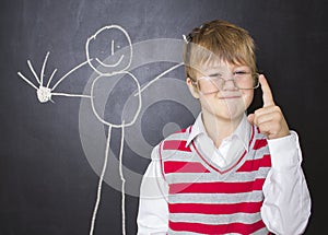 Little boy standing near the blackboard for drawing.