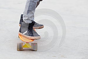 Little boy standing on a orange skateboard outdoors. Closeup ima