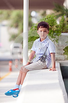 A little boy is standing outside with a walkie-talkie