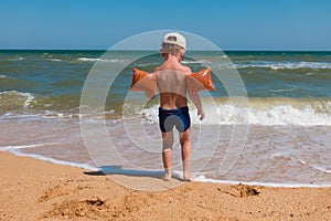 Boy standing on sea coast at surf and looking to water