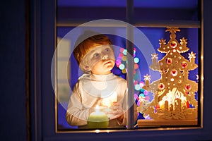 Little boy standing by window at Christmas time