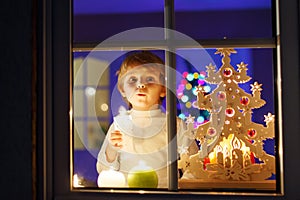 Little boy standing by window at Christmas time