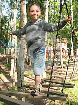 Little boy standing on a wooden ladder and holding the rope